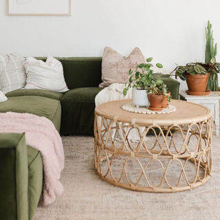 Table d'appoint basse et ronde en rotin, dans un salon avec une plante posée sur la table