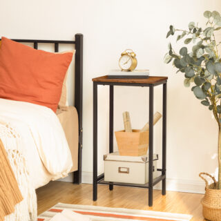 Table d'appoint industrielle à 2 niveaux avec étagère en maille réglable, avec boites rangé dessus, à côté d'un lit, la table fait office de table de chevet