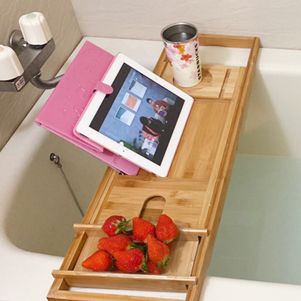 Table d'appoint originale de bain en bois dans un bain blanc qui porte une tablette rose et des fraises