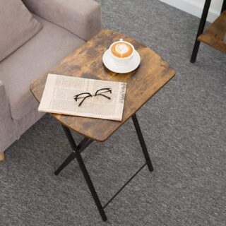 Table d'appoint pliante style industrielle, armature noir et tablette rectangulaire en bois, à côté d'un canapé, avec une tasse de café sur la table