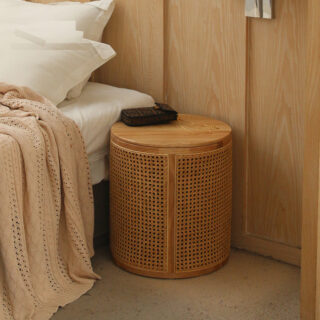 Table d'appoint ronde en rotin au style nordique, avec rangement, forme cylindrique, à côté d'un lit