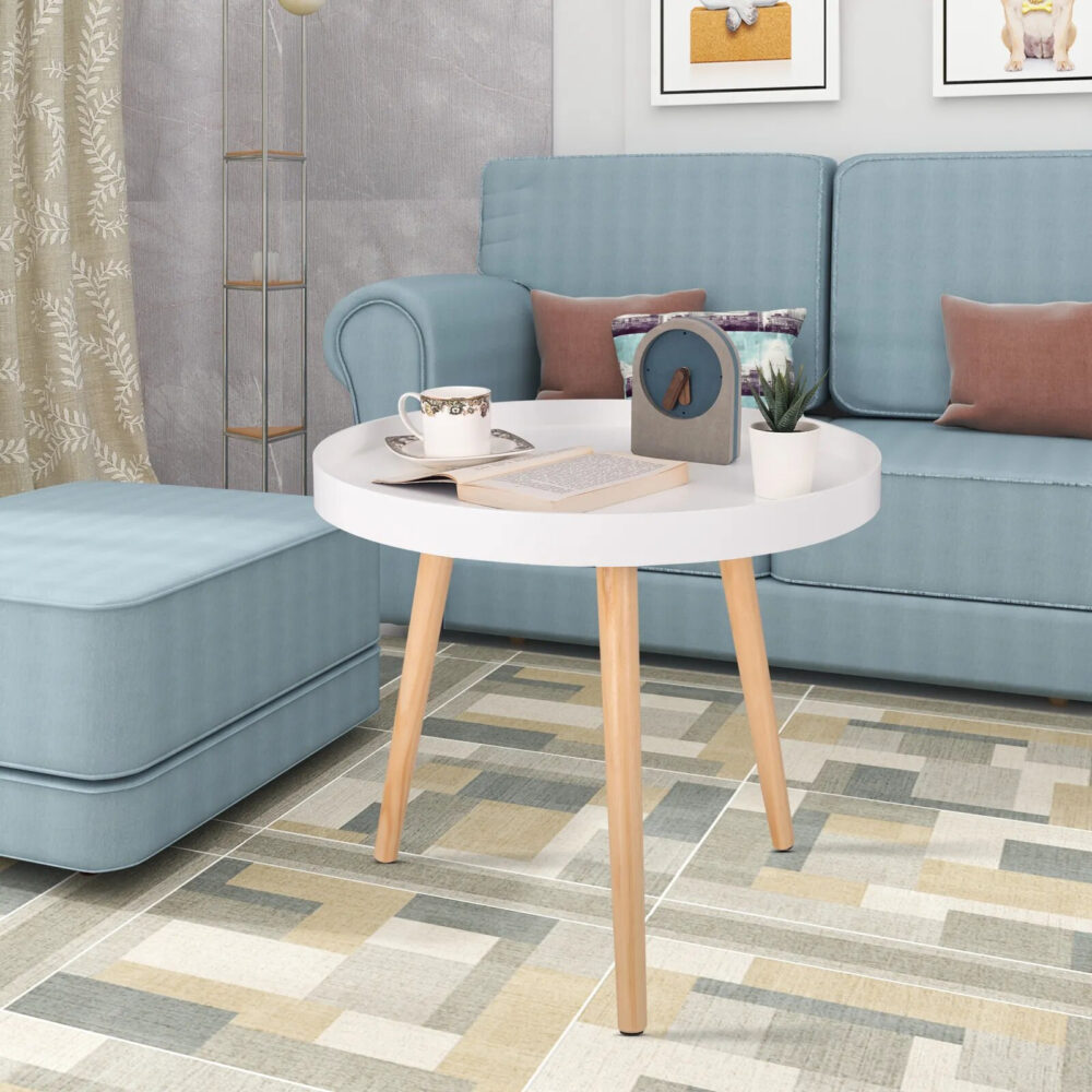 Table d'appoint ronde et basse de style scandinave, de couleur blanche dans un salon devant un canapé bleu